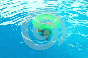 Little child with inflatable ring in outdoor swimming pool