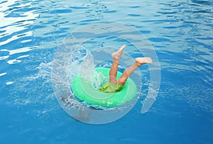 Little child with inflatable ring in outdoor swimming pool