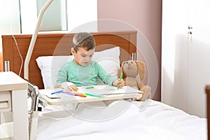 Little child with intravenous drip drawing in hospital