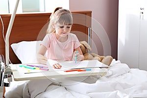 Little child with intravenous drip drawing in hospital