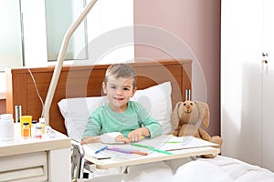 Little child with intravenous drip drawing in bed