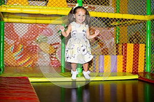Little child jumping at trampoline in indoors playground. Active toddler girl having fun at sport centre.