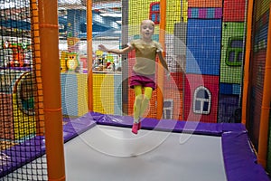 Little child jumping at trampoline in indoors playground. Active toddler girl having fun at sport centre