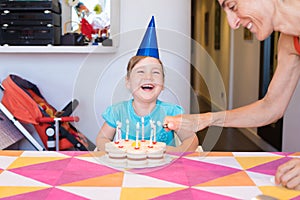 little child laughing and woman lighting candles on birthday cake