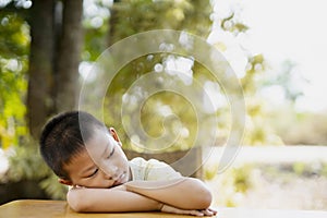 Little child laying his head down on table with sad face.