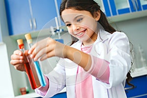 Little child with learning class in school laboratory comparing two liquids