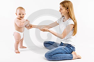 Little child learns to walk with the help of the mother, on a white background