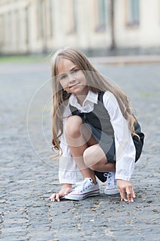 Little child with long hair in school uniform play in schoolyard outdoors, childhood