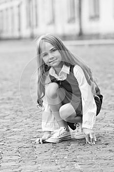 Little child with long hair in school uniform play in schoolyard outdoors, childhood