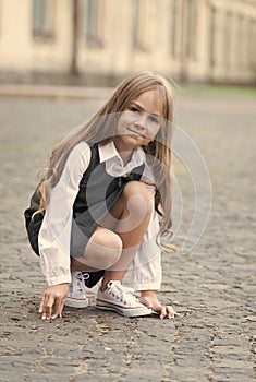 Little child with long hair in school uniform play in schoolyard outdoors, childhood