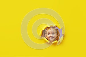 Little child looking, peeping through the bright yellow paper hole. Advertise childrens goods. Wow and shocked funny face.