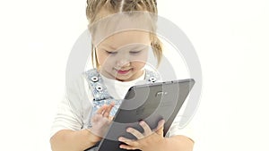 Little child looks interesting pictures on the tablet. White background. Slow motion