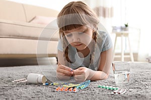 Little child with many different pills on floor. Danger of medicament intoxication