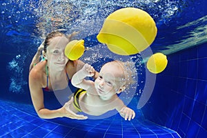 Little child with mother swimming underwater in pool