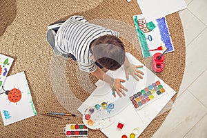 Little child painting on floor at home