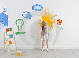 Little child painting wall with roller brush