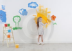 Little child painting wall with roller brush