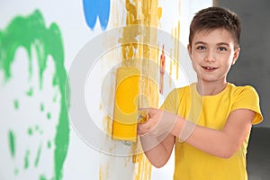 Little child painting wall with roller brush