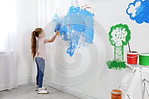 Little child painting wall with roller brush