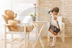 A little child photographer is taking a photo to her teddy bear