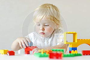 Little child playing with colorful plastic blocks at kindergarten or home. Educational toys for preschooler children. Development