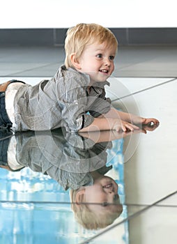 Little child playing with his reflexion on the floor