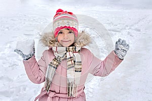 A little child is playing snowballs. The notion of winter rest and children entertainment. A girl with snow in her hands