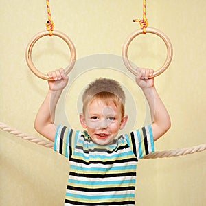 Little child playing sports on gymnastic rings