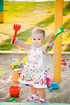 Little child playing with toys in sand on children playground