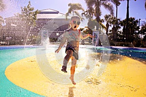 Little Child Playing in Water at Splash Park on Summer Day