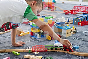 Little child playing with wooden railway on the floor. Little boy playing with wooden train set