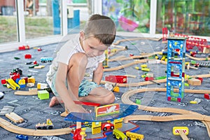 Little child playing with wooden railway on the floor. Little boy playing with wooden train set