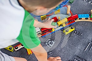 Little child playing with wooden railway on the floor. Little boy playing with wooden train set