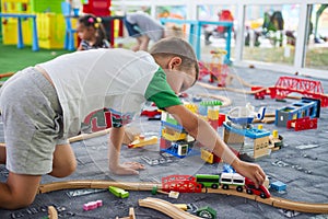 Little child playing with wooden railway on the floor. Little boy playing with wooden train set