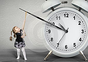 Little child pulling hand clock, time management concept