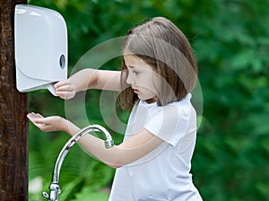 Little child pumping liquid soap for wash the hands in the park. Coronavirus prevention hand hygiene. Concept hygiene. Clean and
