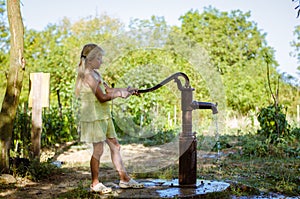 Little child pumping water from the water well