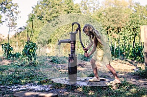 Little child pumping water from the water well