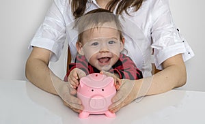 Little child is putting coins in piggy money bank