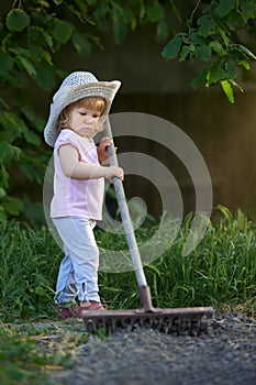 Little child raking up soil and preparing for planting