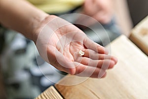 Little child`s hand holds lost tooth. small hand with missing tooth with caries