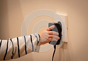 Little child`s hand playing with power socket and electric transformer. Closeup