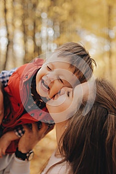 Little child sitting on father`s shoulders. Mother kisses her son