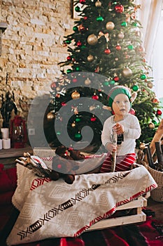 Little child sitting on the floor near the Christmas tree