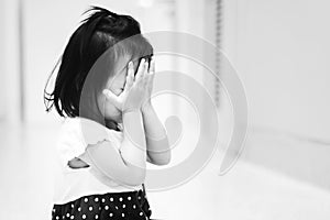 Little child sitting on ground crying and cover her face with her hand