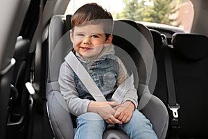 Little child sitting in safety seat inside car. Danger prevention