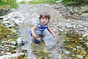 Little child standing in flashy river