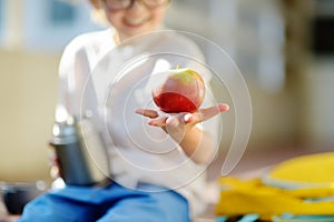 Little child student having lunch on stairs of elementary school building. Healthy meal for schoolkids. Back to school