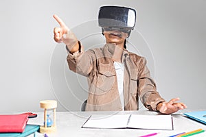 Little child studying with vr glasses for homework and online classes at desk. Young girl with headset preparing for