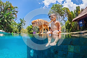 Little child swim with dog in blue swimming pool